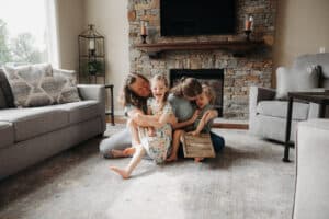 Family of four enjoying quality time together in a cozy living room, surrounded by comfortable furniture and a stone fireplace.